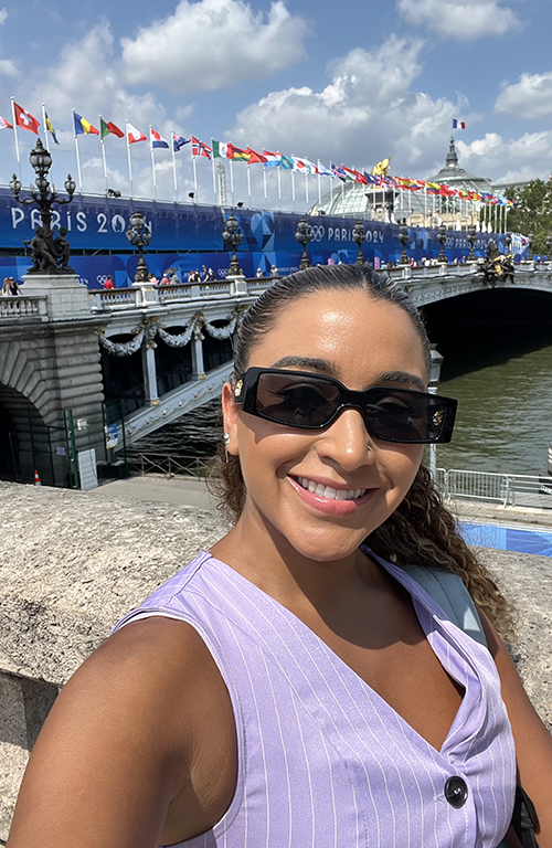Vanessa Perdomo in front of a bridge with the text Paris 2024.