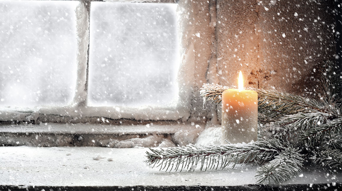 A snowy scene featuring a candle and a window.