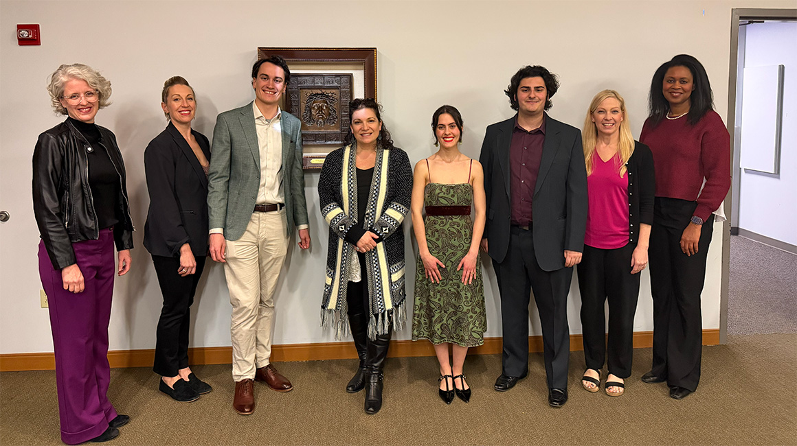 Eight people pose for a photo. Among the eight are the three winners, the judge, and various faculty members.