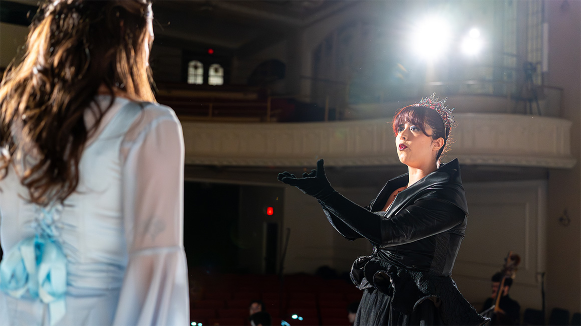 Two people singing on stage. The shot was taken from the stage toward the hall, and the lights can be seen in the background.