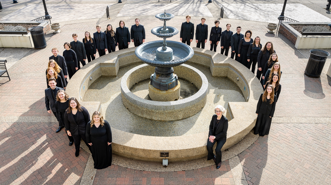 Voices of Spirit poses for a group photo around a fountain..