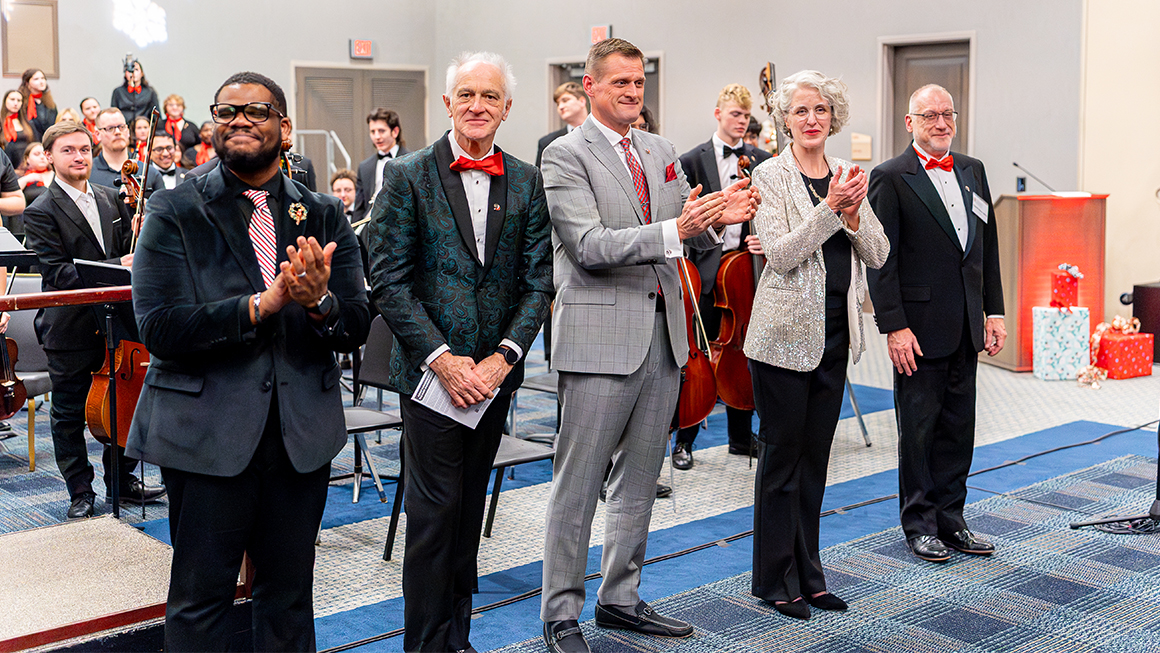 Applause line of conductors and guests standing before the orchestra after a holiday concert.