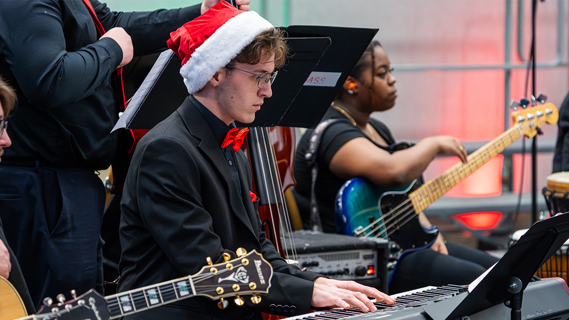 Keyboardist in Santa hat plays alongside guitar and bass.