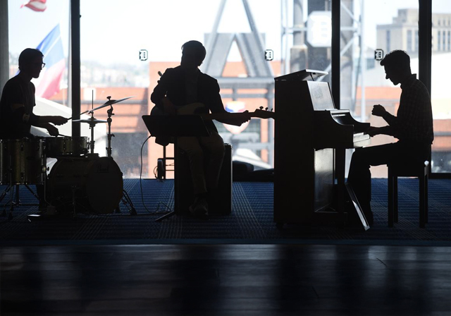 A trio of musician silhouettes performing.