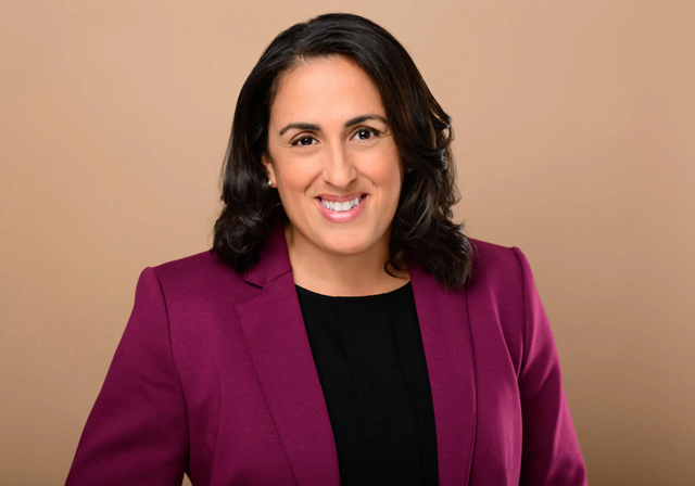 A person wearing a magenta blazer poses for a photo.