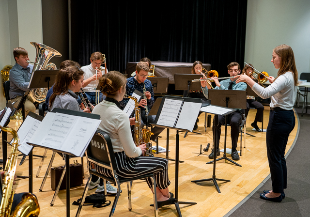 A student conducts a group of other students in a performance.