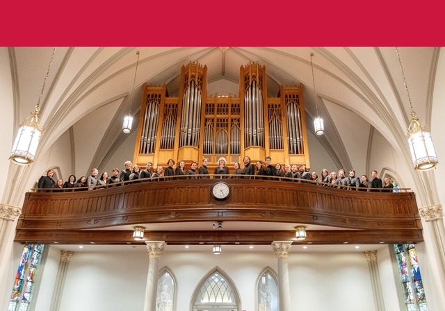 A group of people pose on a balcony near a pipe organ.