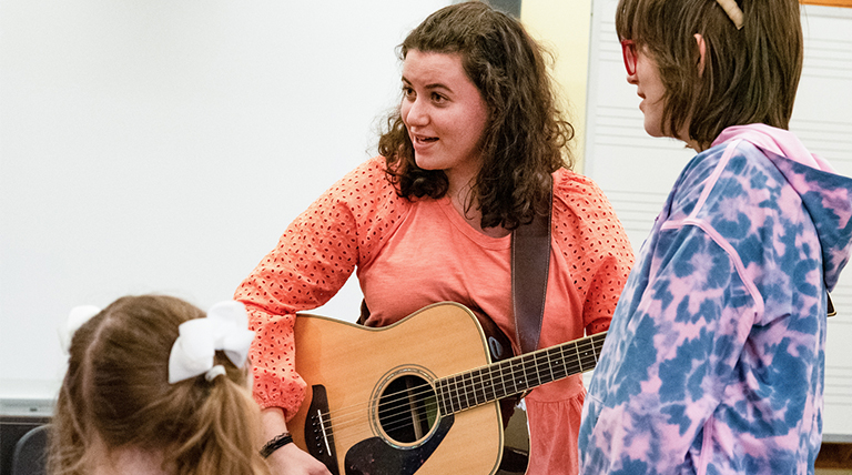 A person plays an acoustic guitar in a music therapy setting.