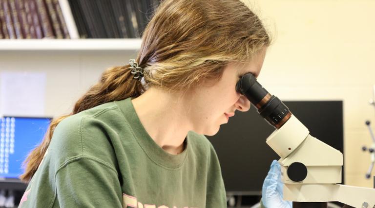 a girl looking in a microscope