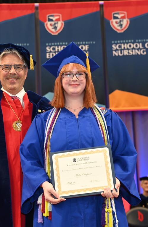student holding up an award