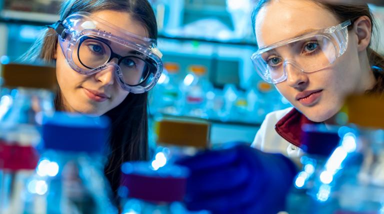 two people looking at a beaker