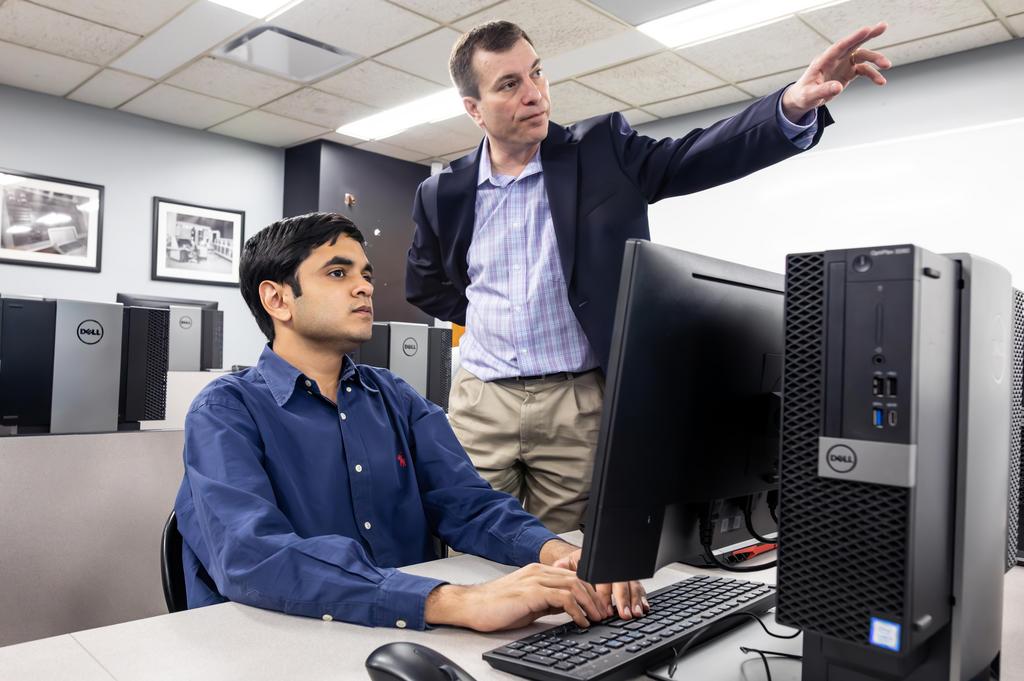 a male pointing to a laptop