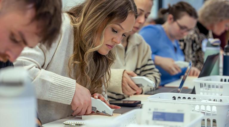 A row of nursing students at a table focused on working.