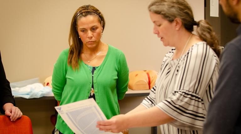 A nursing instructor works with a graduate student. 