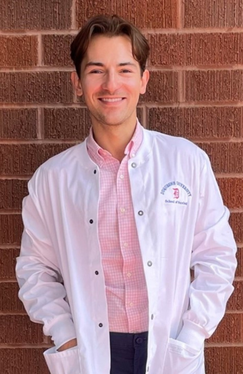 male nusre smiling while wearing white coat