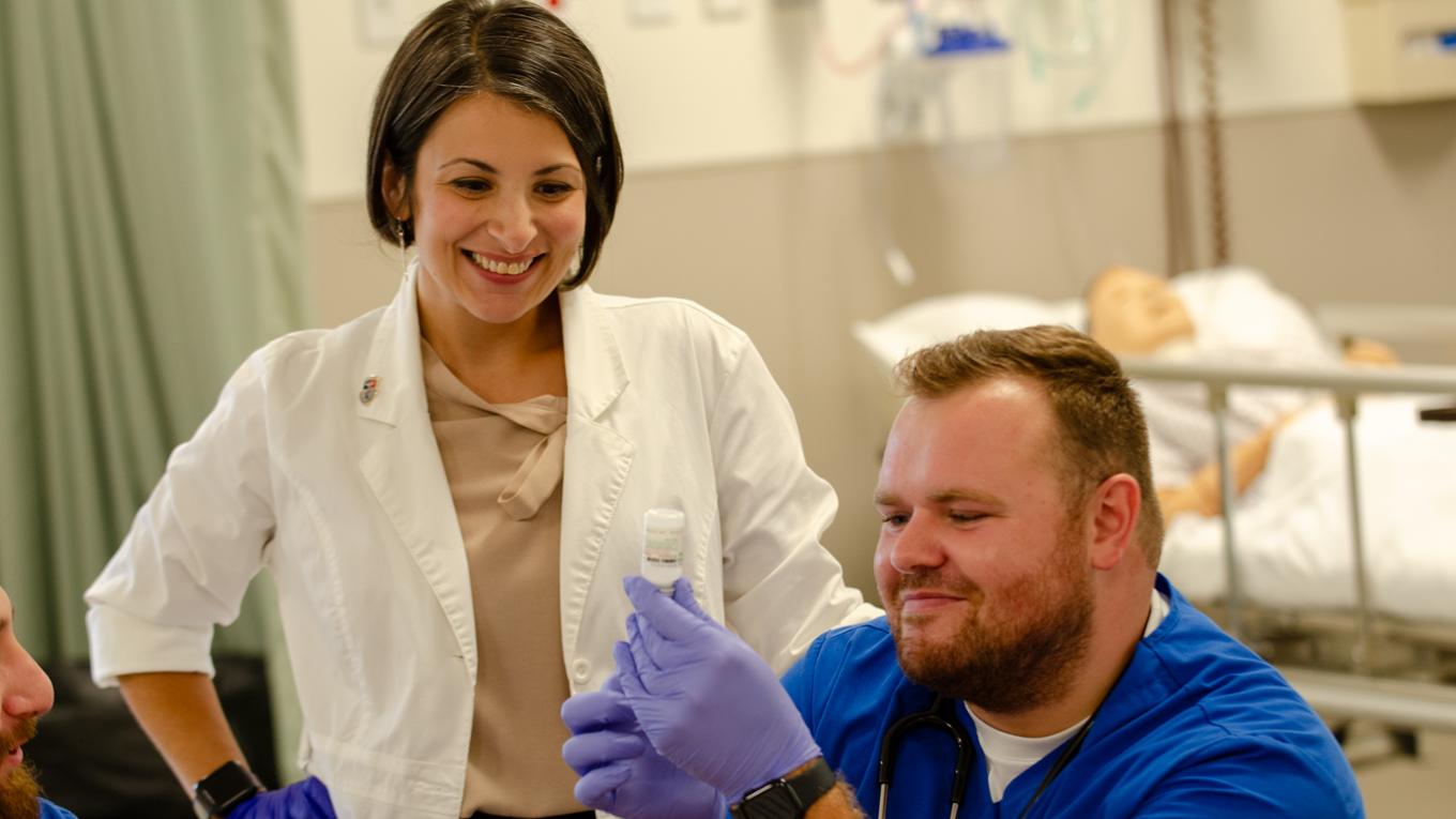 A nursing instructor works with a student to practice injections. 