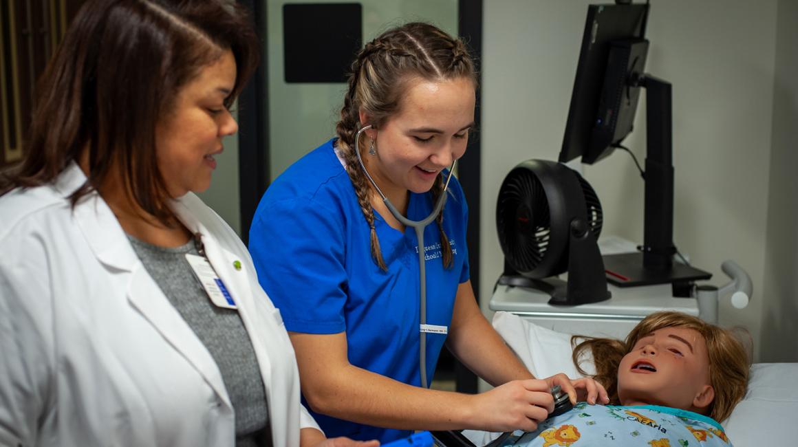 A nursing student works on an exercise with her instructor.