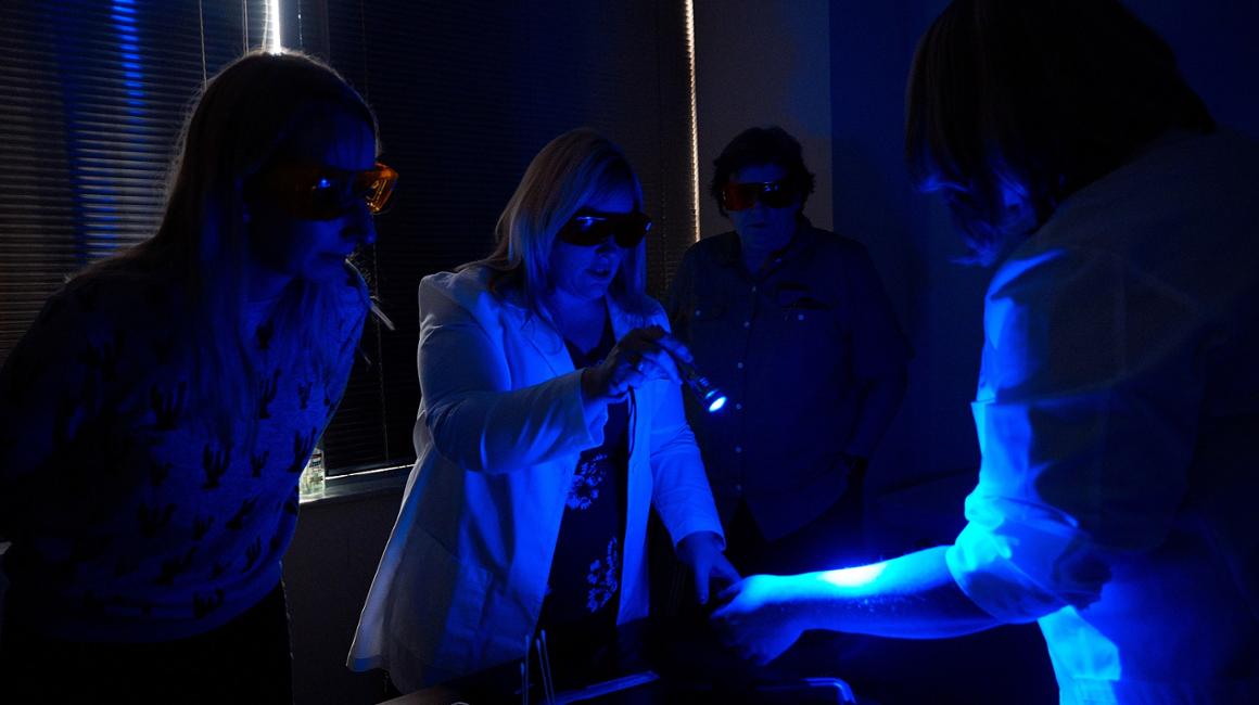 Nursing students work under a UV light.