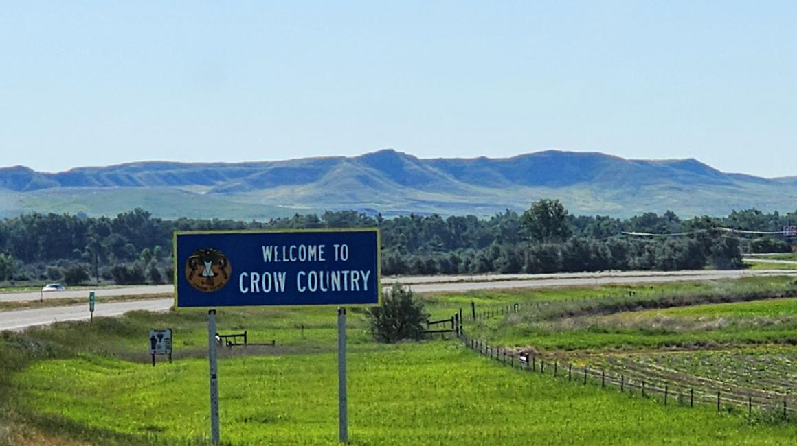 welcome to crow country sign with a mountain range in the back