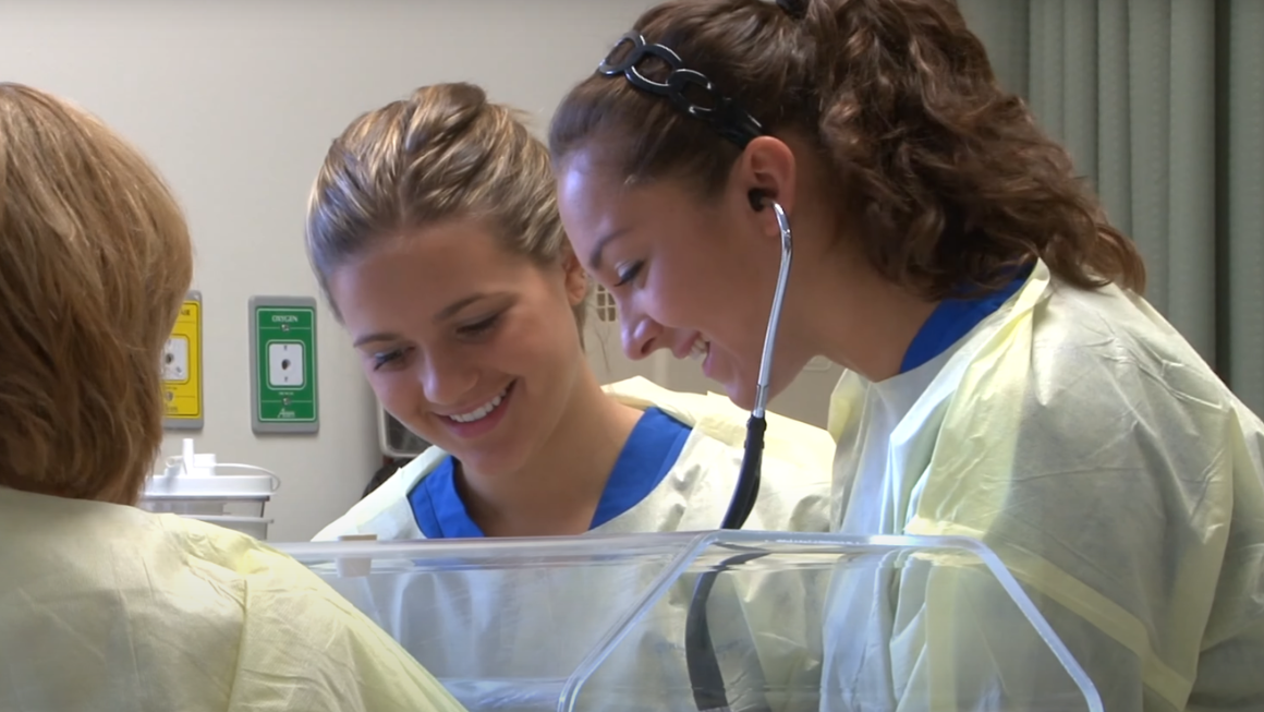 Two nursing students in scrubs smiling.