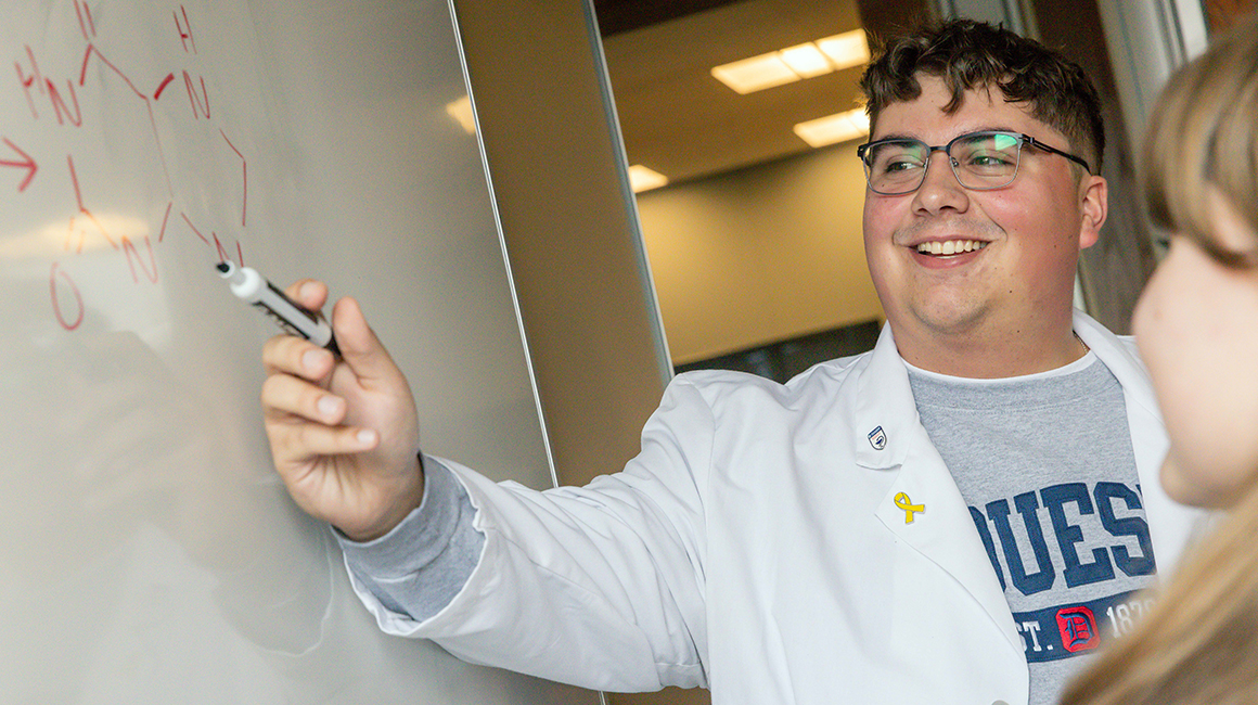 a student pharmacist tutoring a fellow student pharmacist