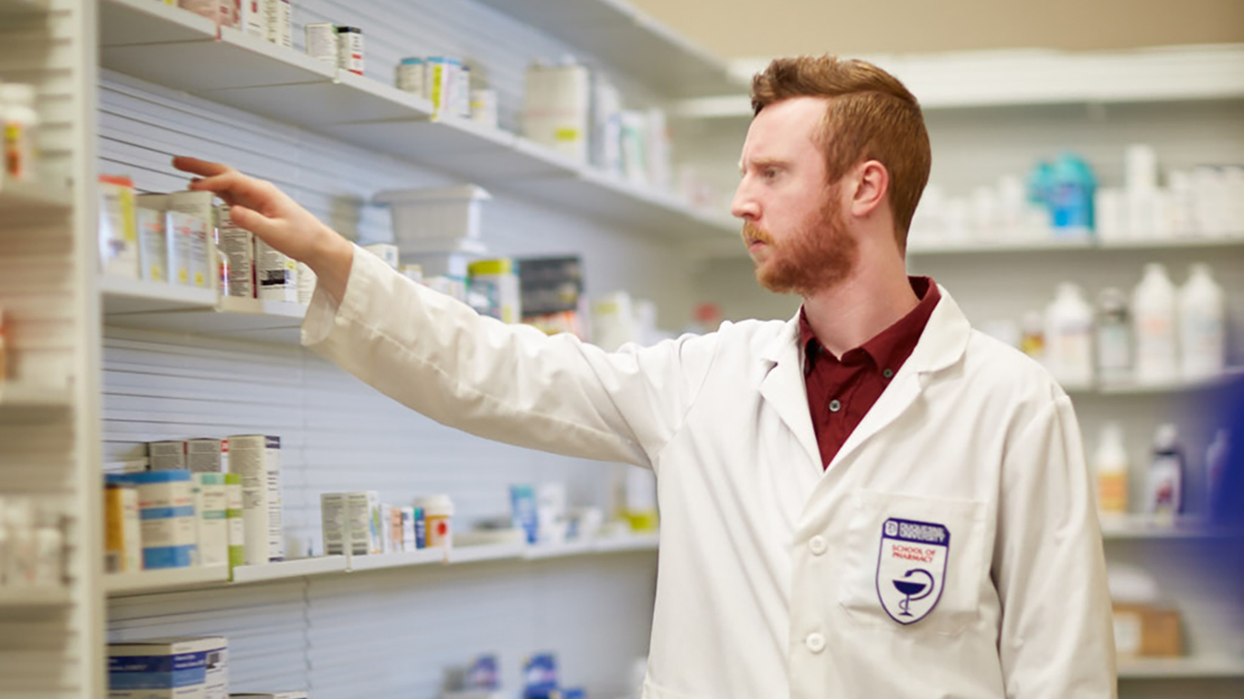 Duquesne pharmacy student stocking shelves in a pharmacy