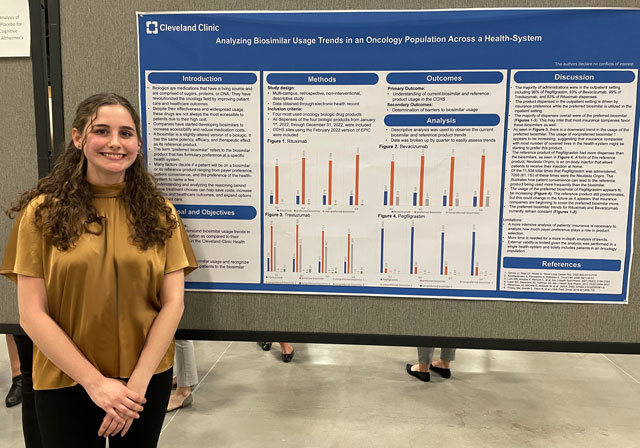 student standing beside her research poster