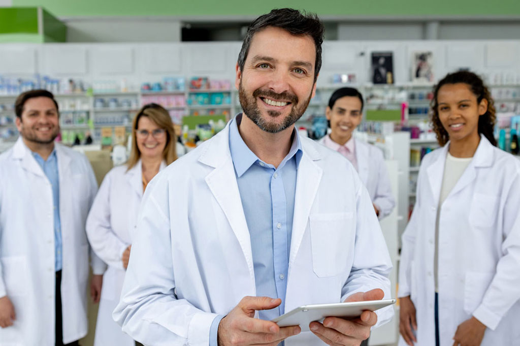 male pharmacist smiling at camera as four pharmacists stand in the background