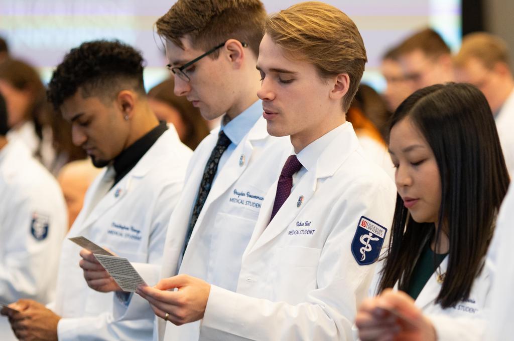 people in white coats taking an oath