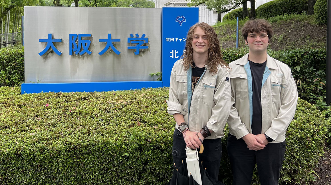 Jacob Dulya and Gabe Pecar posing in front of sign during internship in Japan