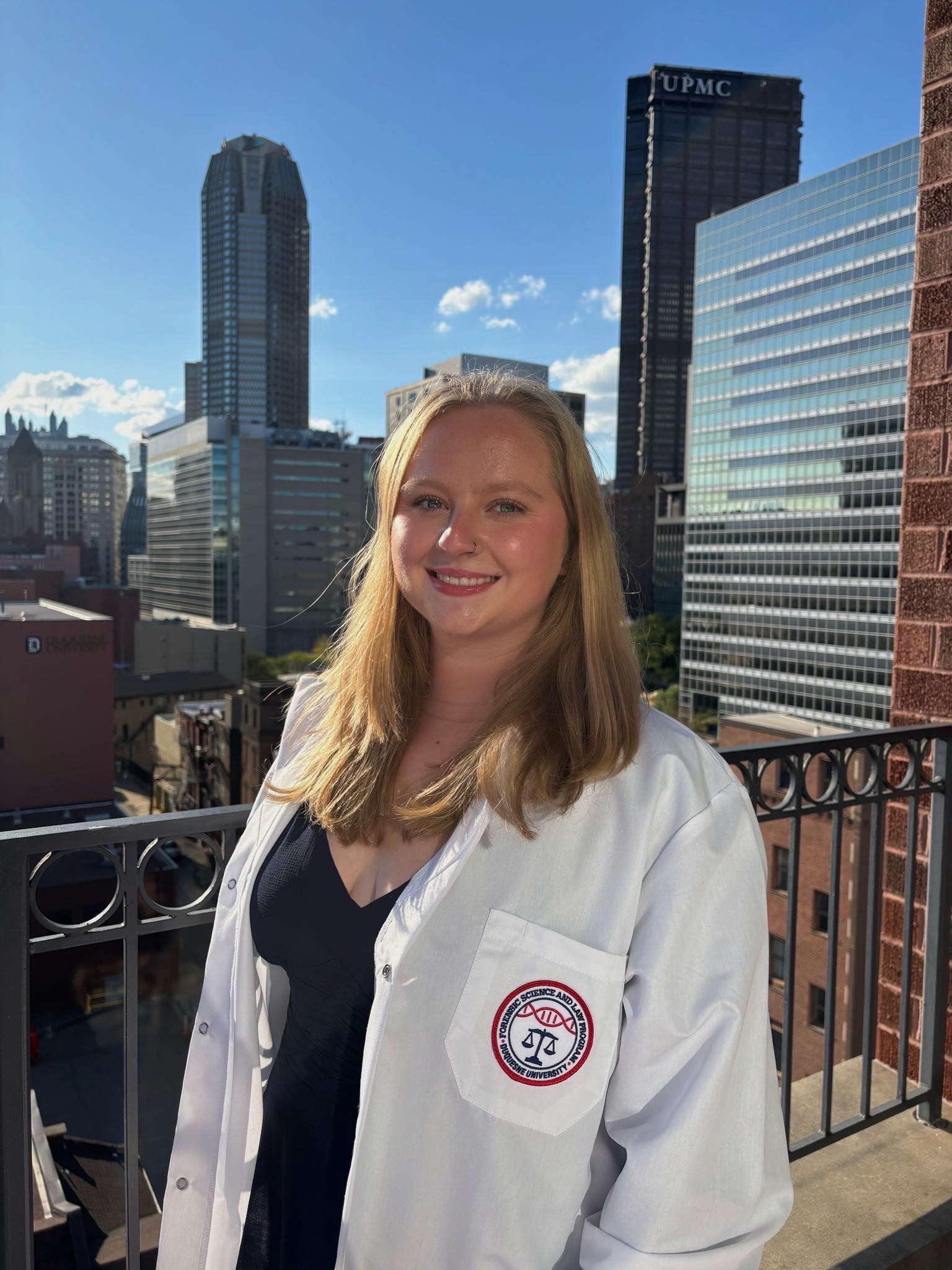 a girl in a white jacket in front of large buildings