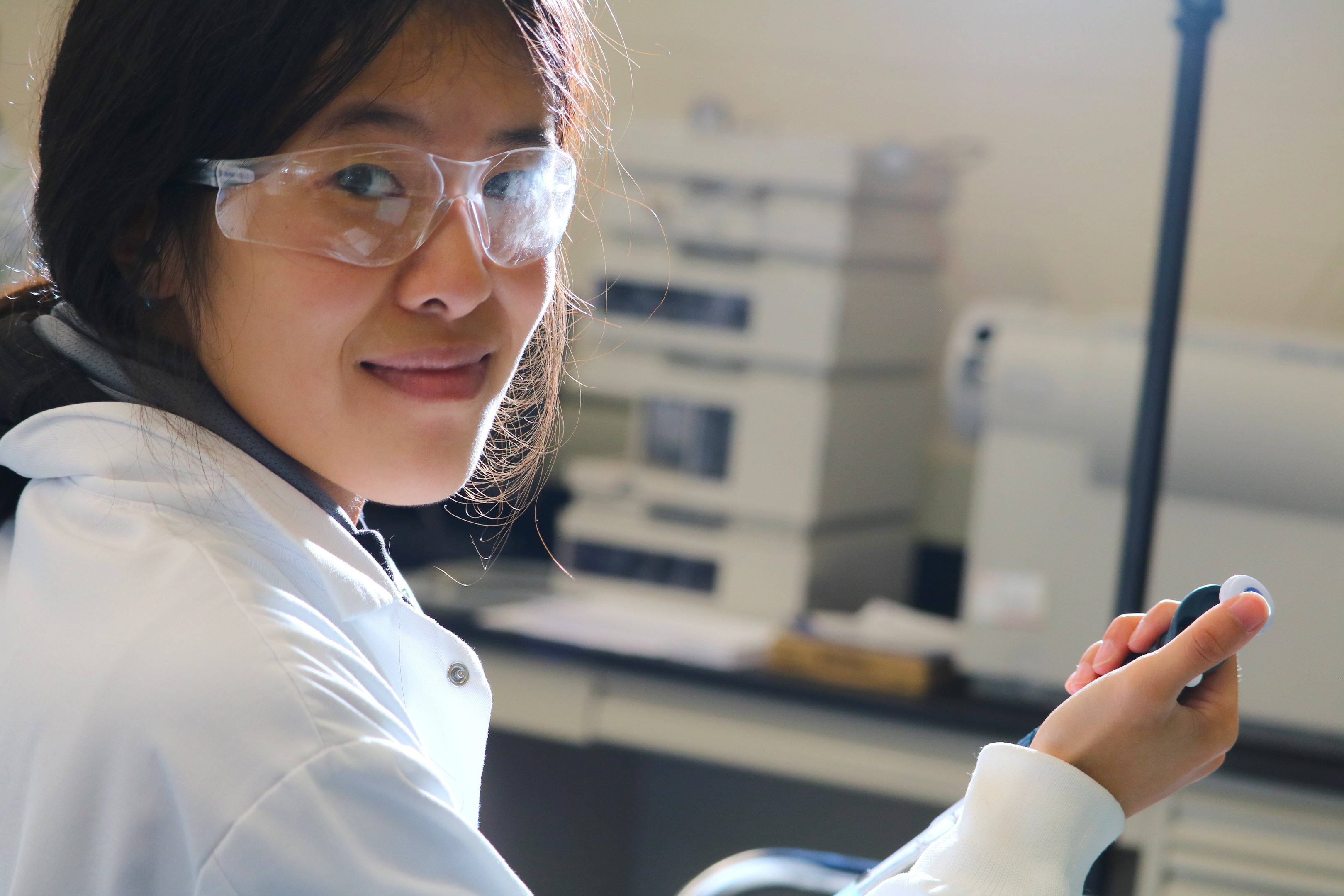 girl wearing safety glasses holding a beaker