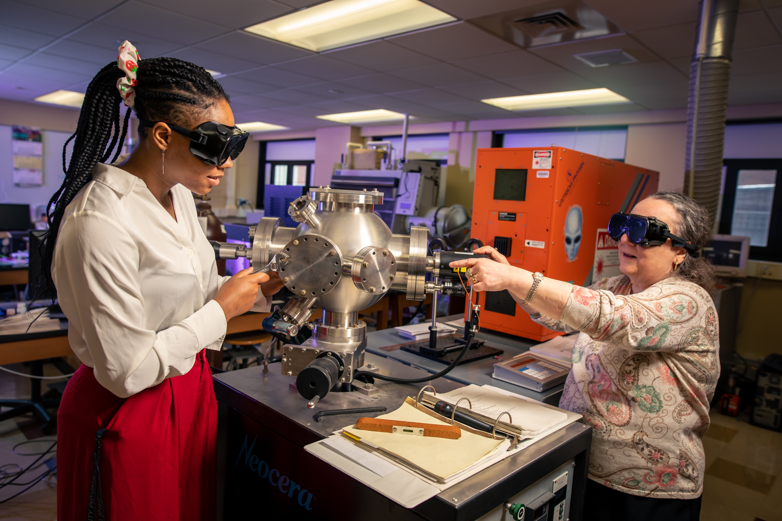 a student and a professor wearing goggles working with equipment