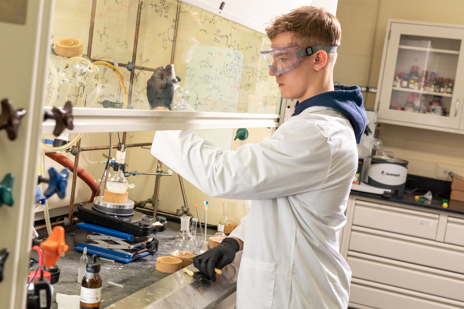 a student in a white coat in a glove box