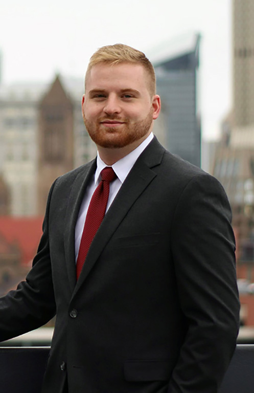 Zachary Valkovci pictured on Duquesne campus with Pittsburgh skyline in background