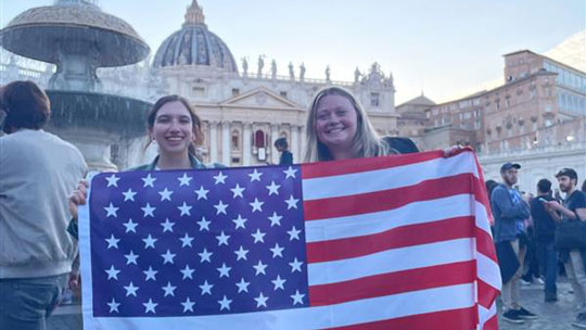 Two students hold the American flag while in Rome.