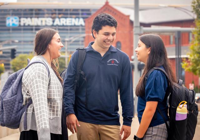 Duquesne students talking with PPG Paints Arena in the background.