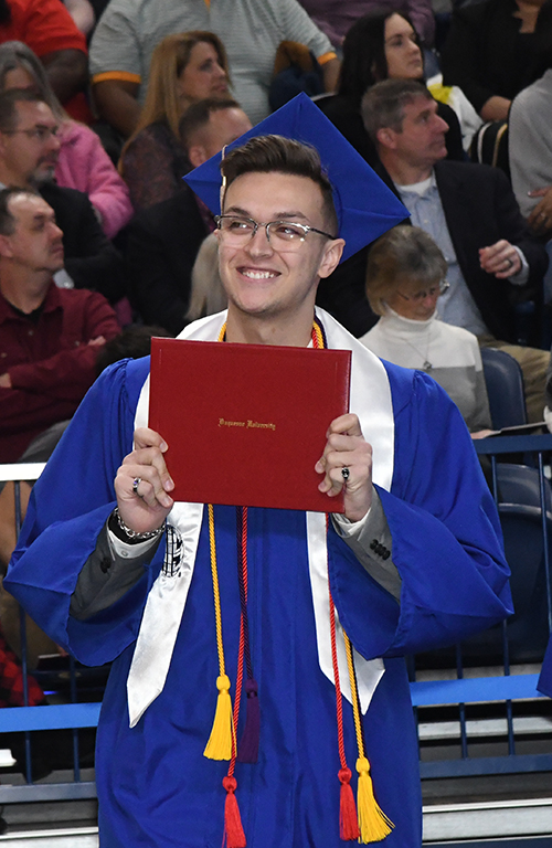 Roberto Laporte holding diploma and smiling at his 2022 Commencement.