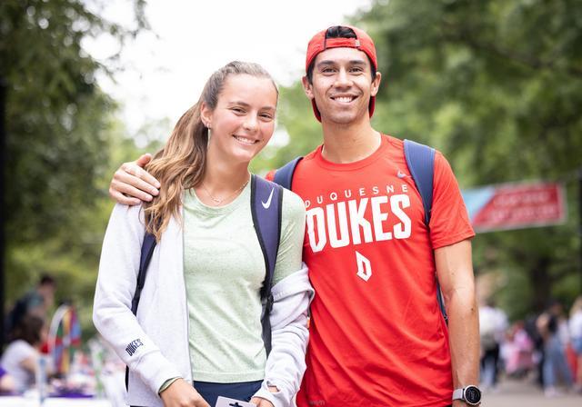 Two Duquesne standing together outside on the University's Academic Walk.