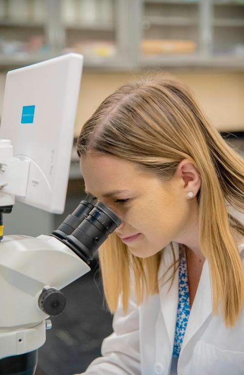 Madison Uhrin looking through a microscope.