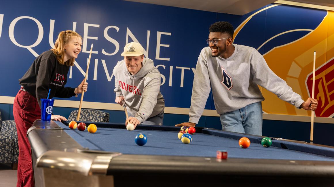 Duquesne students playing pool and laughing in the Union's NiteSpot.