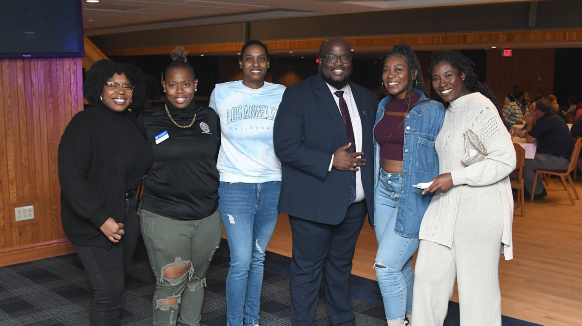 Six people standing together smiling at an event