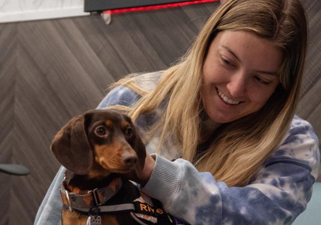 Blond female student holding a brown daschund