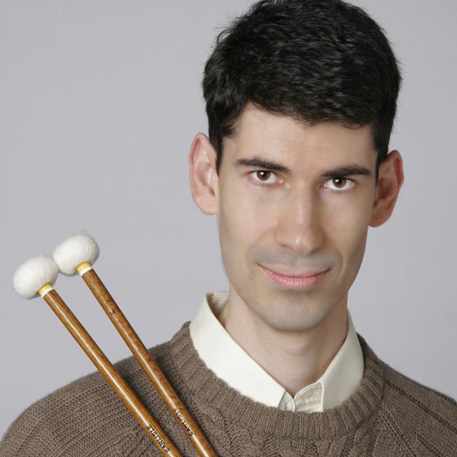 man in brown sweater holds percussion mallets.