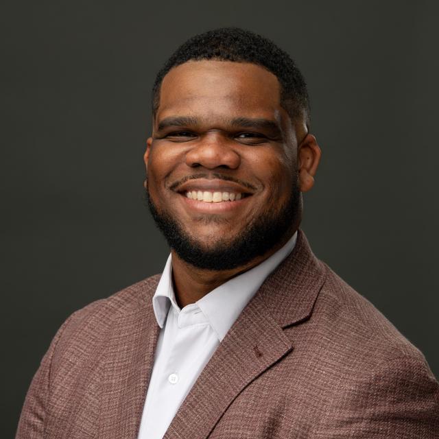 ethan smiling in front of a gray background