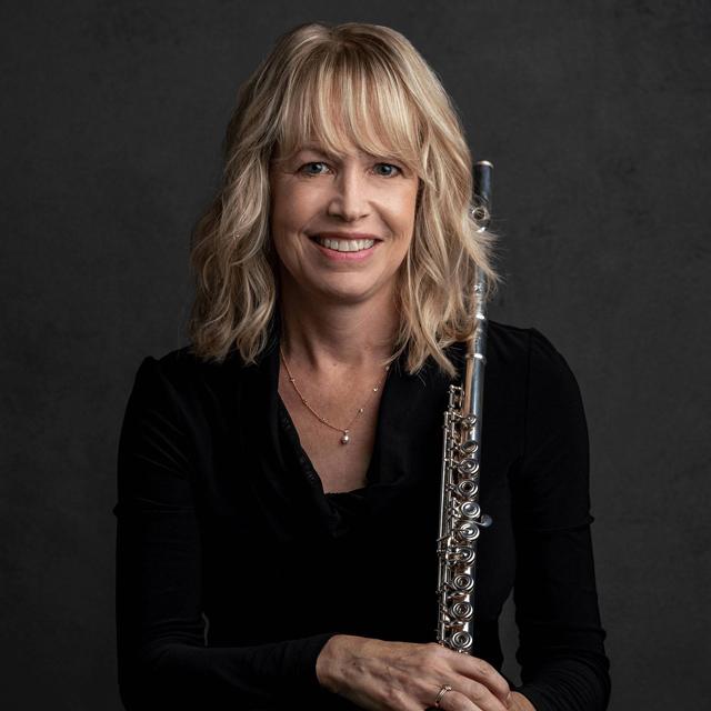 Jennifer Steele poses with flute in front of a gray background.