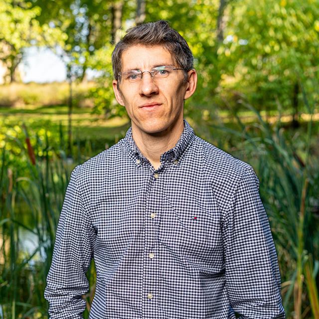 Joseph Sheehan poses for a headshot in front of a blue background.