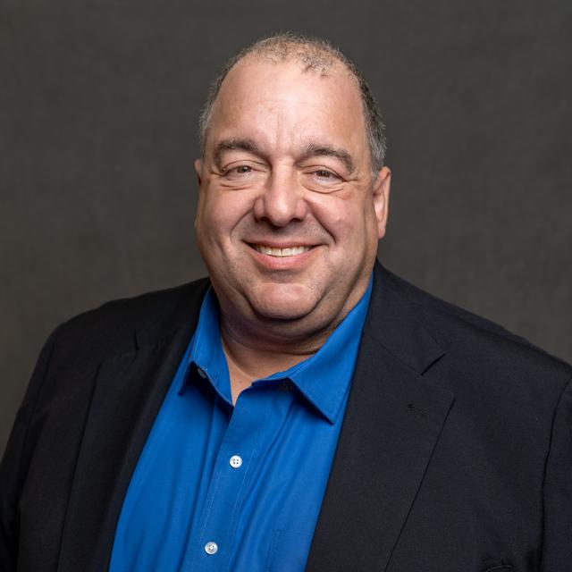 Steve Benham poses for a headshot in front of a gray background.