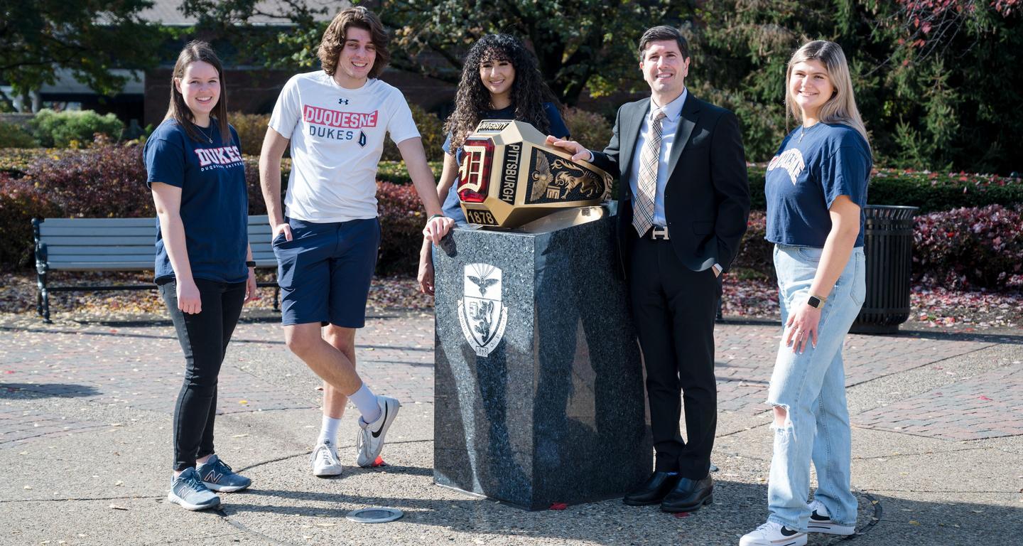 David Dausey standing with students by the big Duquesne ring on campus.
