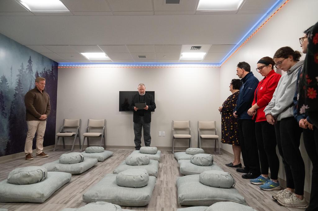 A room with meditation cushions, relaxing murals, and people enjoying the space.